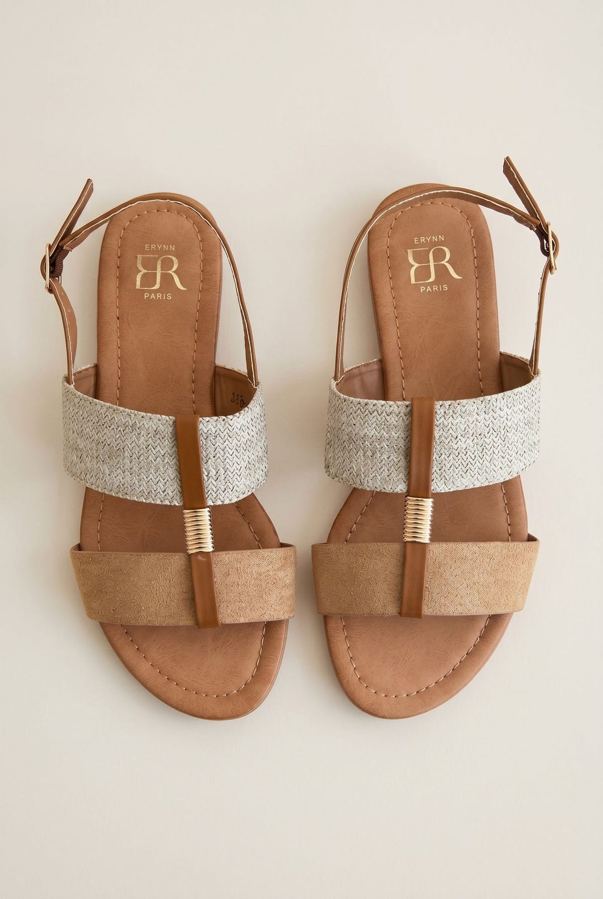 Top-down view of pair of flat sandals with woven straw band and camel suede toe strap, tan leather straps with gold coil and buckles