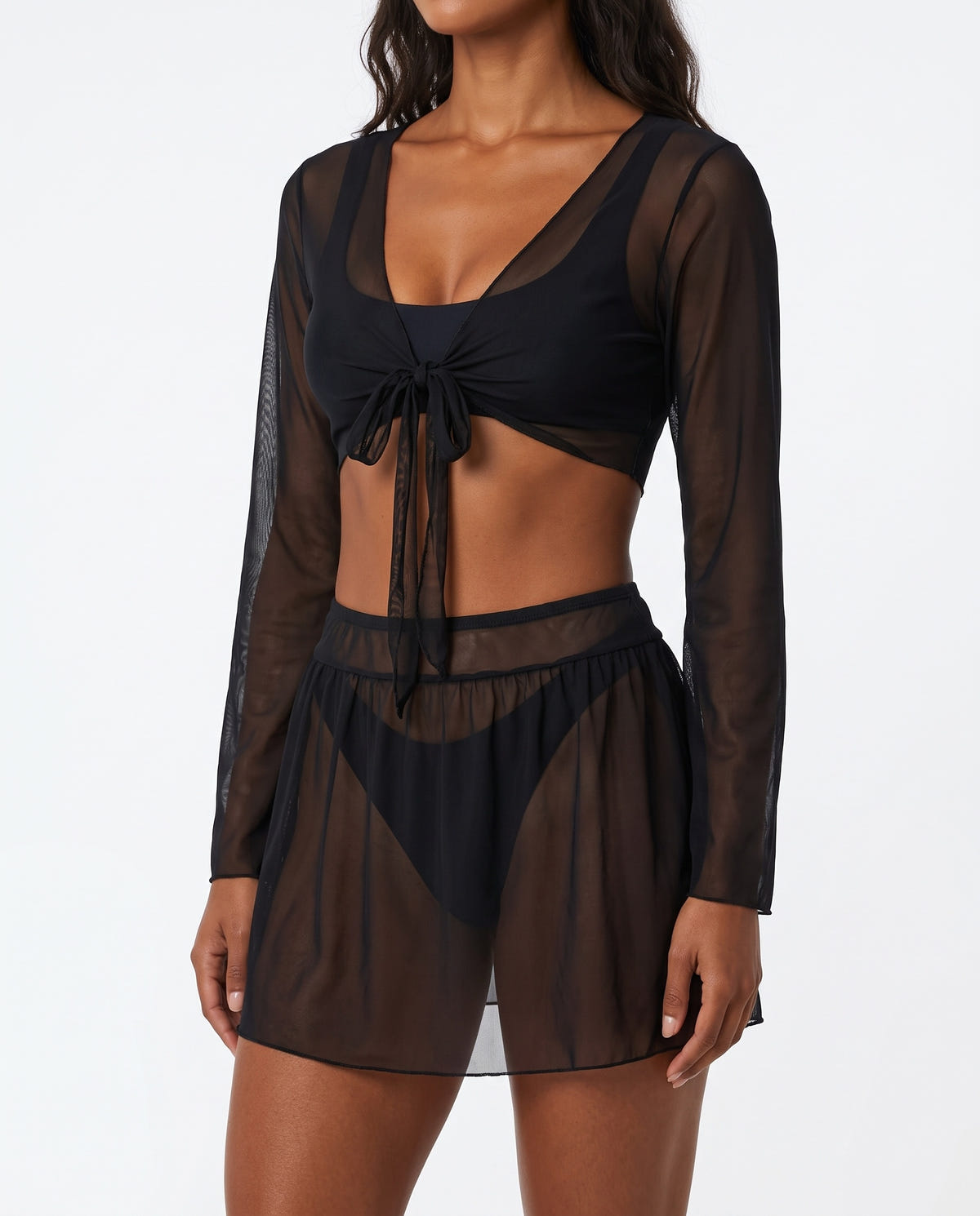 Model wearing black sheer long-sleeve tie-front crop top and mesh mini skirt, front view