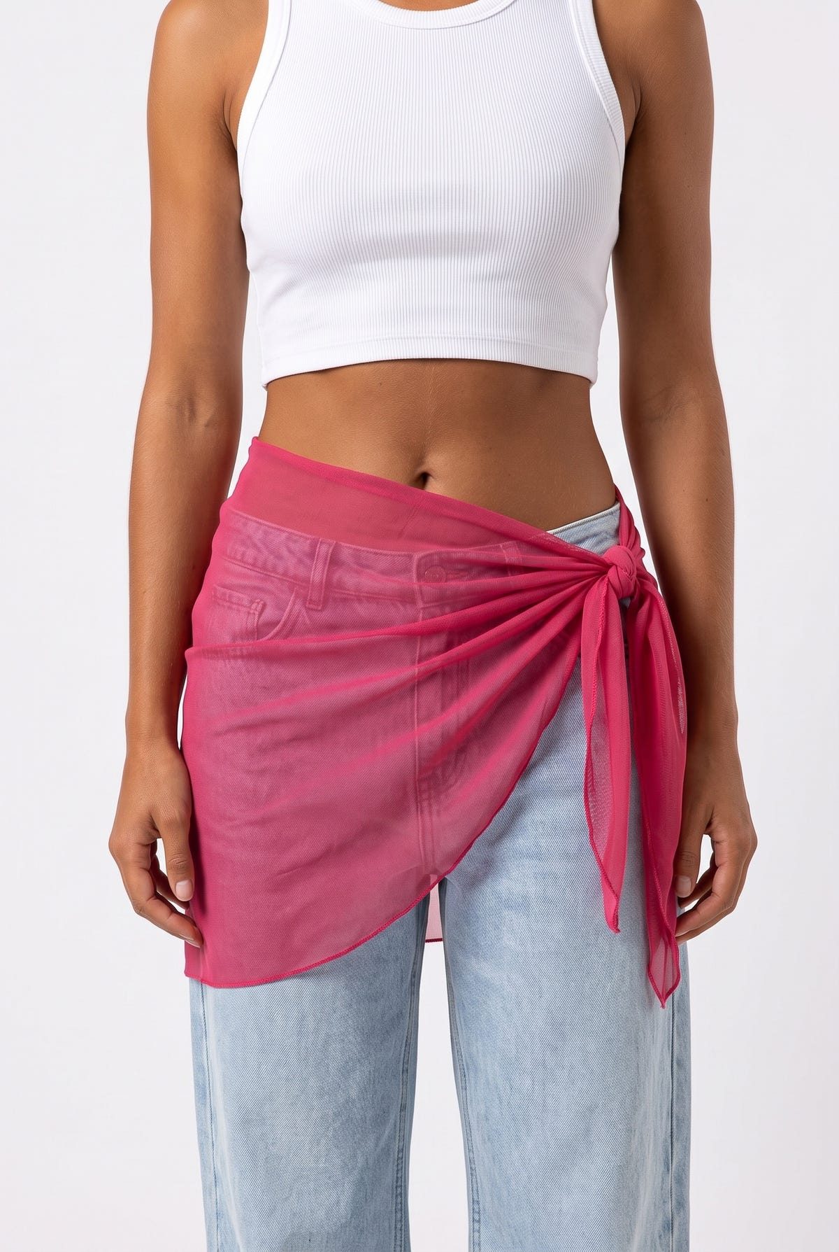 Front view of model wearing fuchsia mesh mini pareo tied at the hip over light blue jeans and white crop top