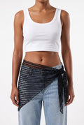 Front view of model wearing black sheer lace sarong tied at the hip with white crop top and blue jeans