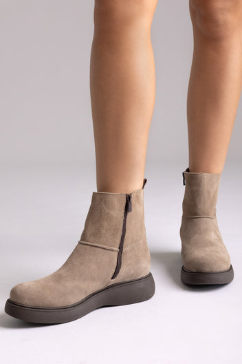 Taupe suede ankle boots worn, front view highlighting rounded toe and flat sole