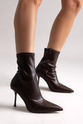 Black stretch pointed-toe ankle boots with stiletto heel, angled view on a model in studio light