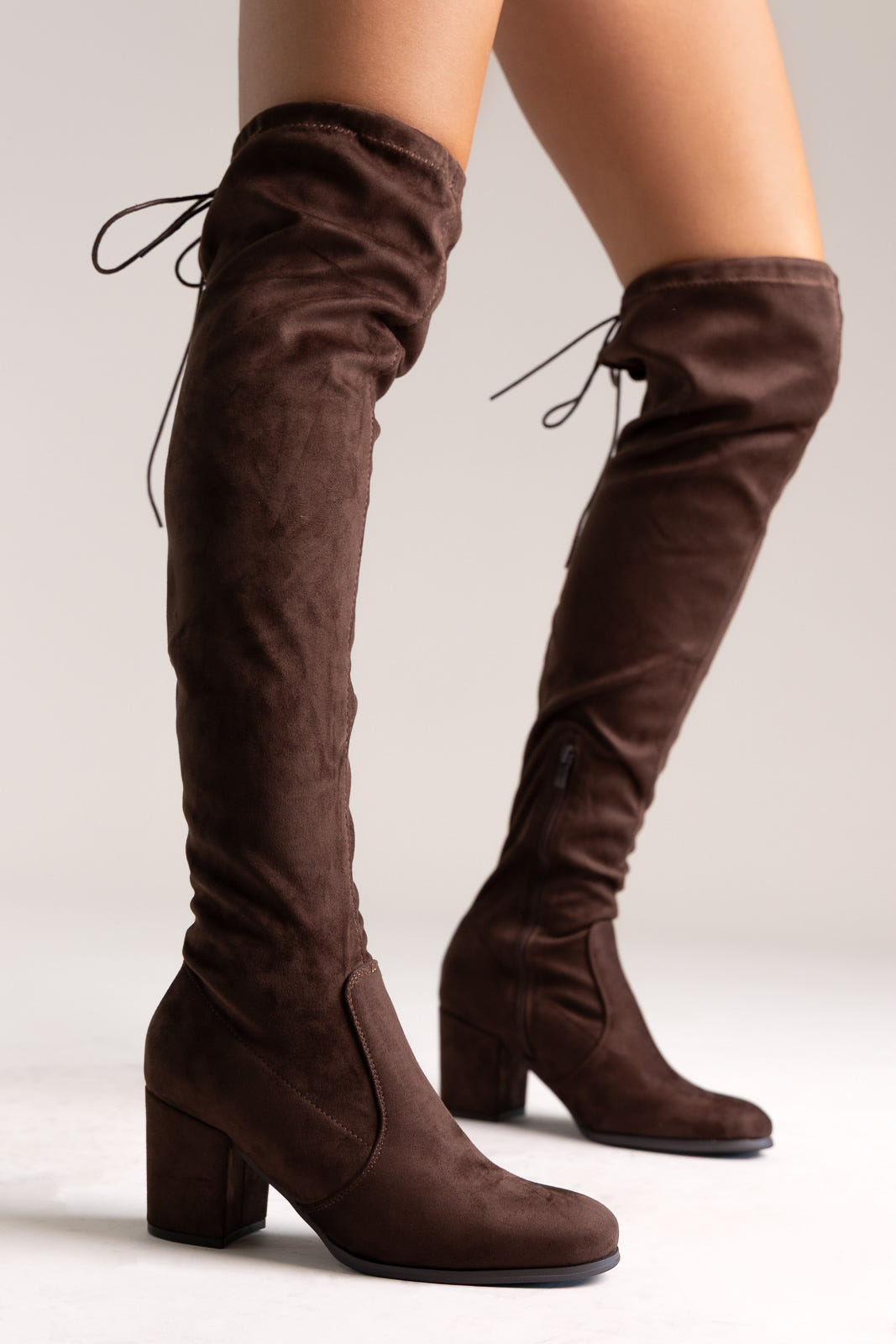 Brown faux suede over-the-knee boots with drawstring tie and block heel, side view on a model