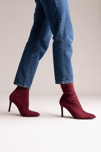 Dark burgundy faux suede stiletto ankle boots with pointed toe, rear view on a model in jeans