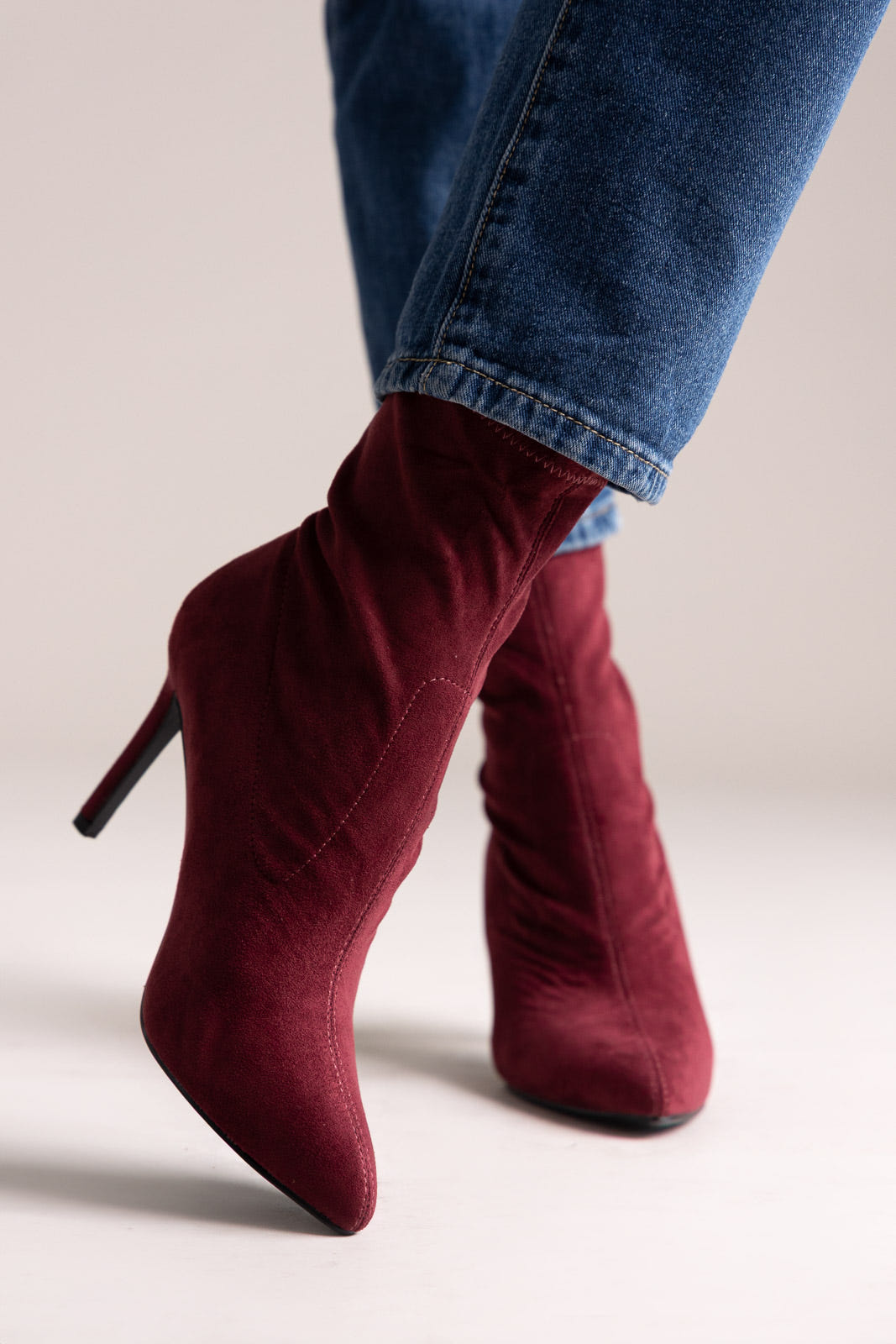 Tan faux suede western ankle boots with stitched shaft and stacked block heel, side view on a model in jeans