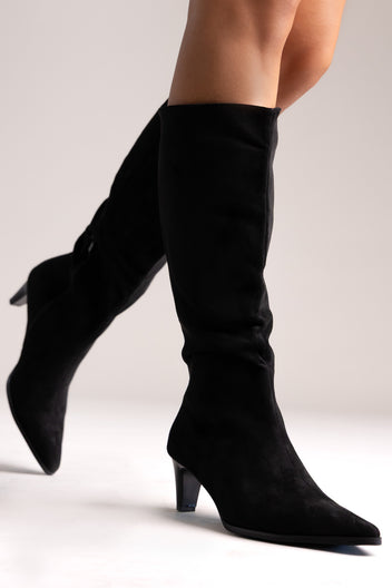 Black faux suede pointed-toe knee-high boots with kitten heel, side view on a model