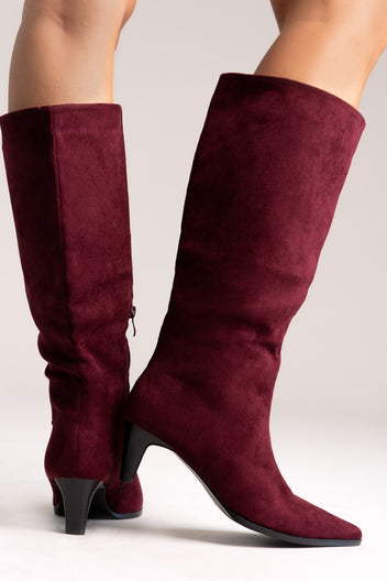 Burgundy faux suede pointed-toe knee-high boots with kitten heel, side view on a model