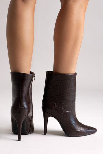 Dark brown croc-embossed pointed-toe ankle boots with side zip and stiletto heel, angled view on a model