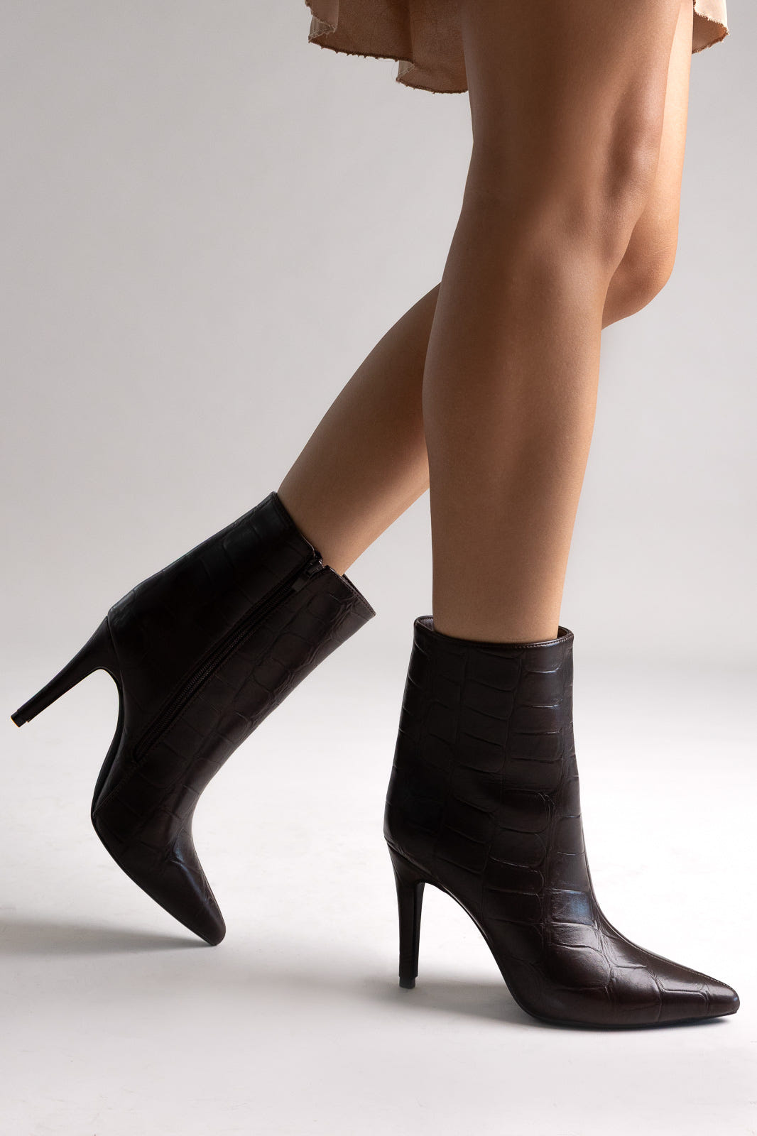 Black leather pointed-toe ankle boots with stiletto heel and side zip, angled view on a model