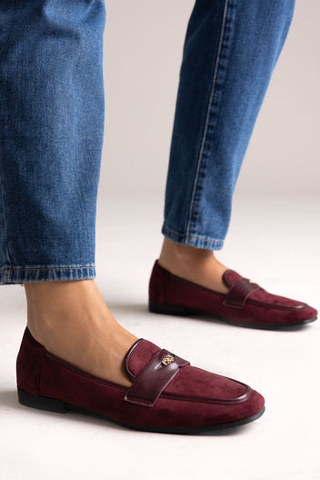 Burgundy suede penny loafers with leather trim and gold-tone bit, side view on a model