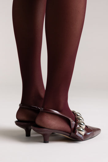 Burgundy leather pointed-toe slingback kitten heels with silver ball-chain strap, rear view on a model
