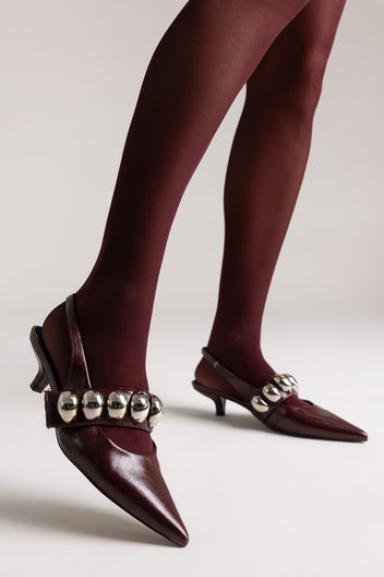 Burgundy leather pointed-toe slingback kitten heels with silver ball-chain strap, front view on a model
