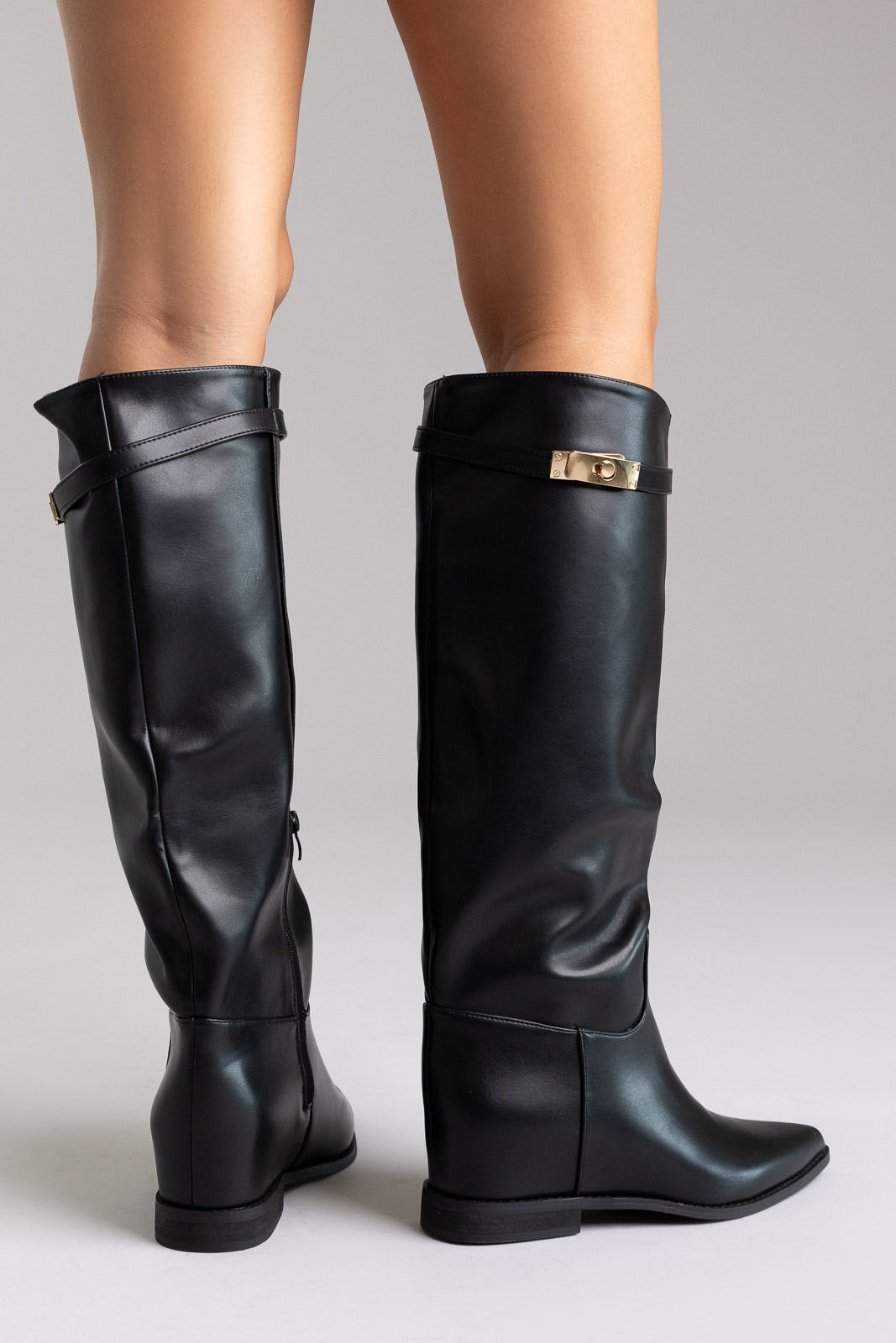 Black leather knee-high boots with gold buckle detail and block heel, angled view on a model