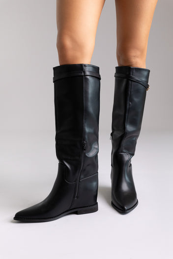 Black leather knee-high boots with pointed toe and wide shaft, angled view on a model in studio light