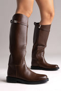 Brown leather knee-high riding boots with silver buckle strap and flat sole, rear view on a model