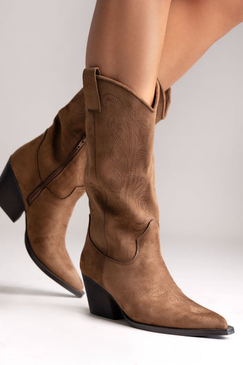 Tan faux suede embroidered western knee-high boots with stacked heel and pointed toe, side view on a model