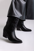 Black faux leather knee-high western boots with block heel and stitched shaft, angled view on a model