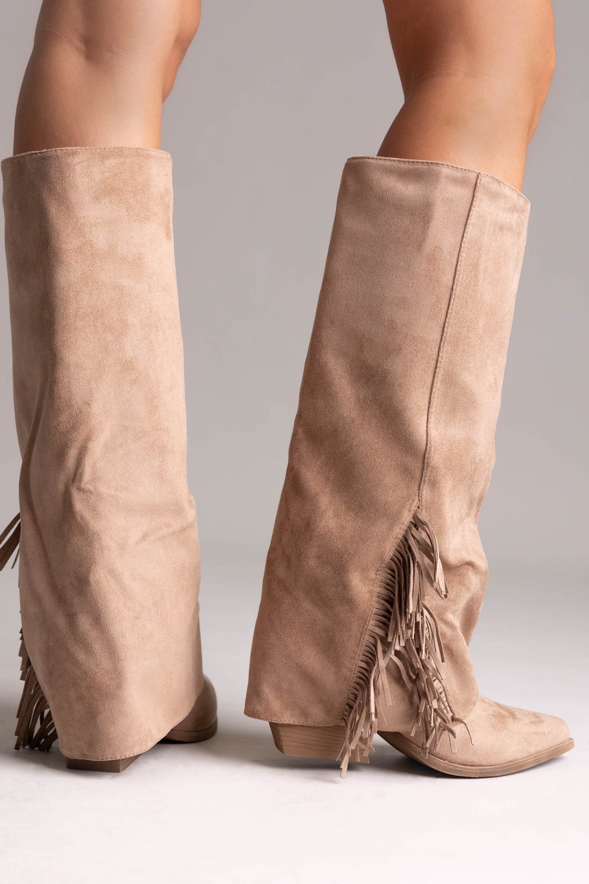 Taupe suede fold-over knee-high boots with fringe trim on the cuff, rear view on a model