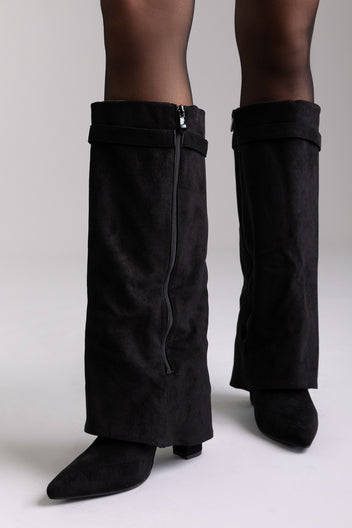 Black suede fold-over knee-high boots with gold buckle and pointed toe, front view on a model in sheer tights