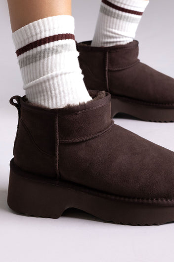 Dark brown suede platform mini ankle boots with striped socks, angled view on a model