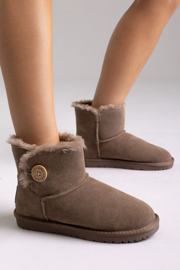 Taupe suede shearling-lined mini ankle boots with button detail, side view on a model in studio light