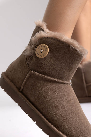 Taupe suede shearling-lined mini ankle boots with button detail, close-up on a model