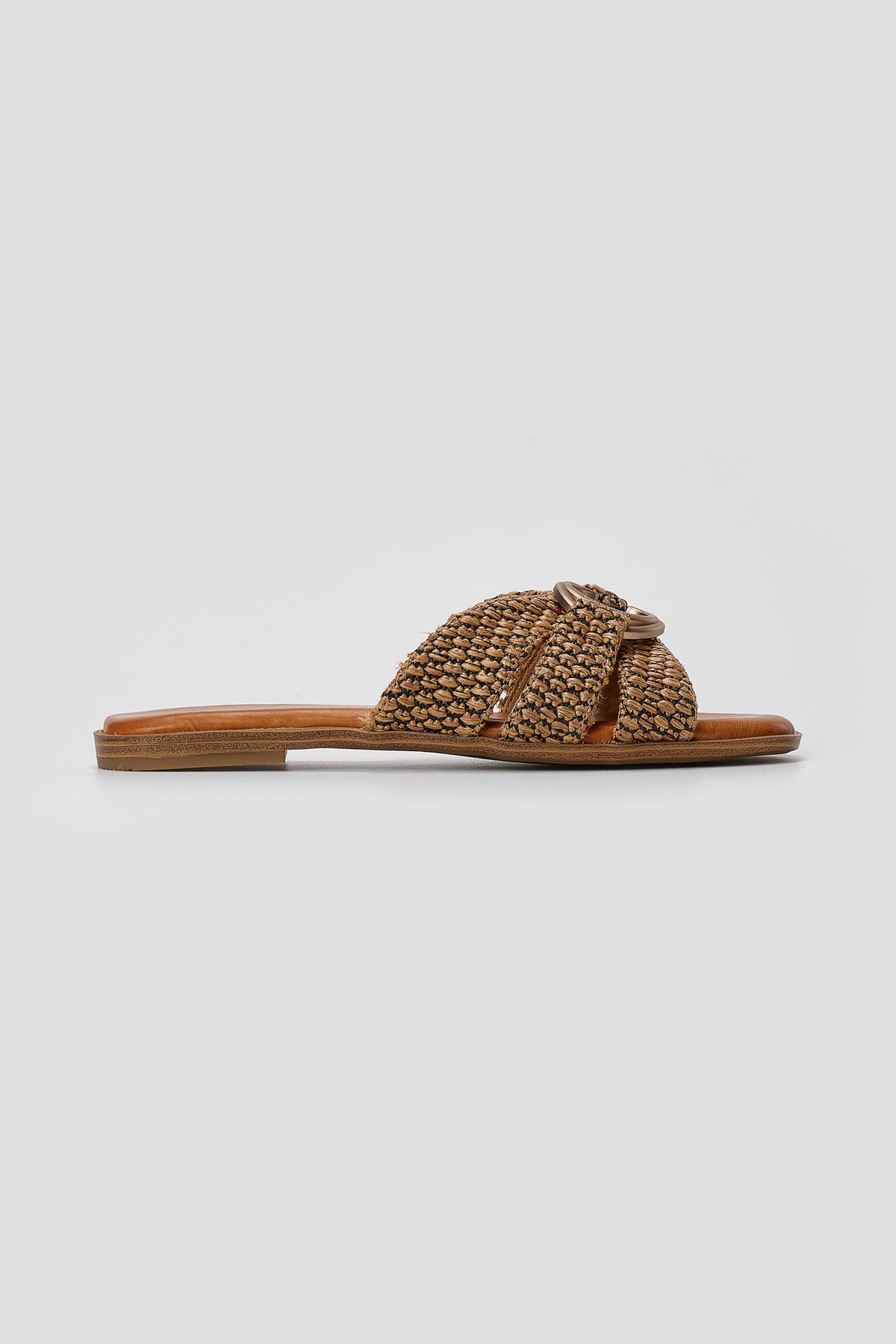 Tan leather flat slide sandal with crossed woven straps and small gold ring detail, side view
