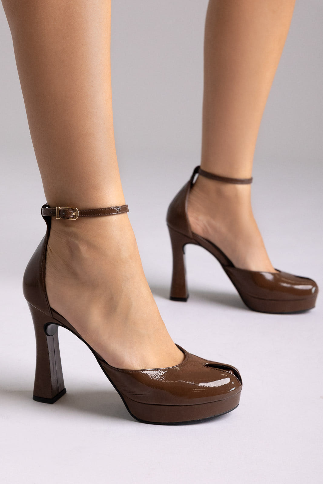 Brown patent leather ankle-strap platform pumps with block heel, front view on a model