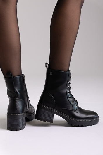 Model legs in black leather lace-up ankle boots with chunky block heels and sheer tights, angled view on a light background