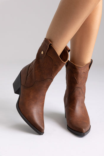 Brown leather western mid-calf boots with block heel and pointed toe, angled view on a model in studio light