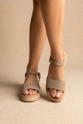 Front view of taupe suede chunky-sole sandals with a wide band and a buckled ankle strap, worn on a model