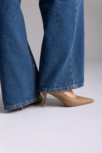 Tan leather pointed-toe kitten-heel pumps, angled view on a model in wide-leg jeans