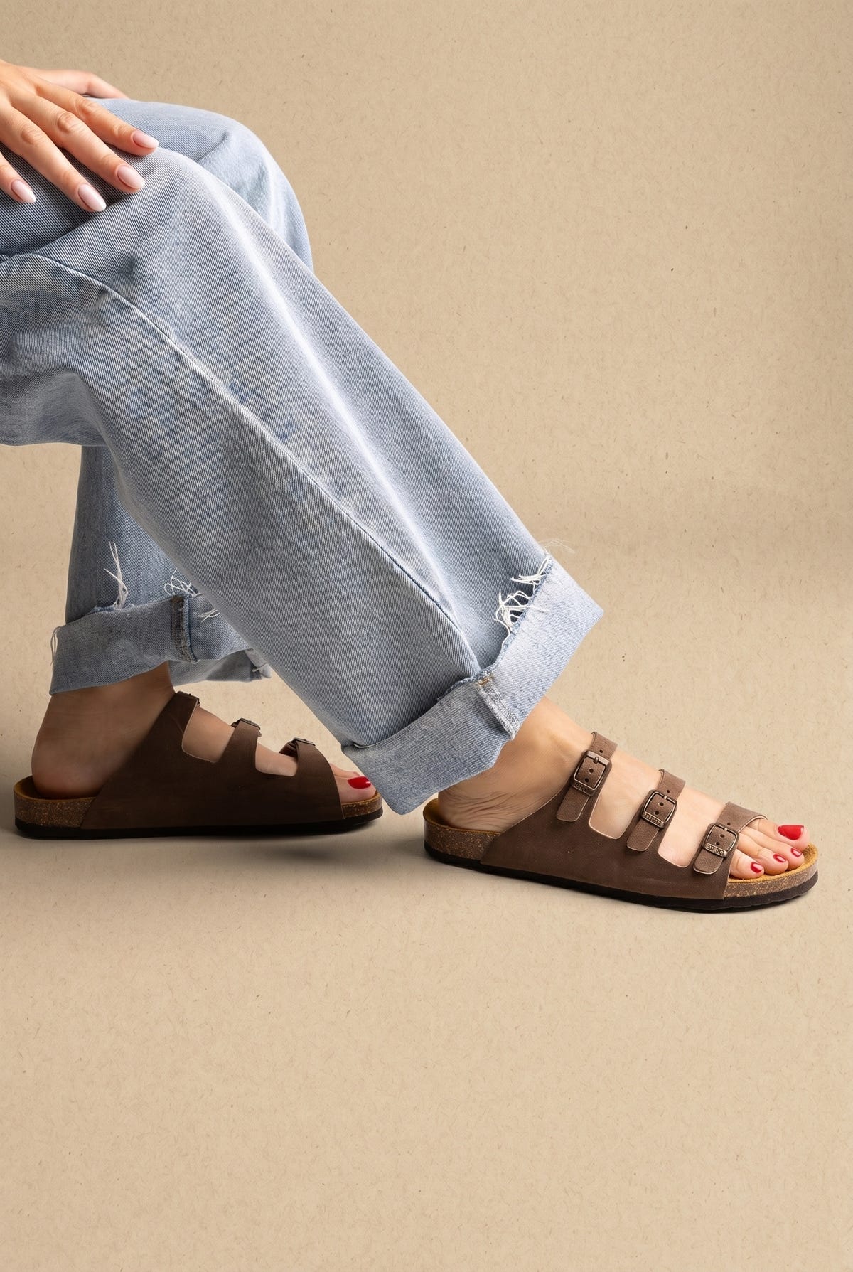 Brown nubuck three-strap buckle sandals with cork footbed, side view worn with rolled jeans on a model