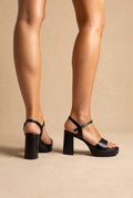 Black leather block heel platform sandals with a single wide toe band and buckled ankle strap, side and back views