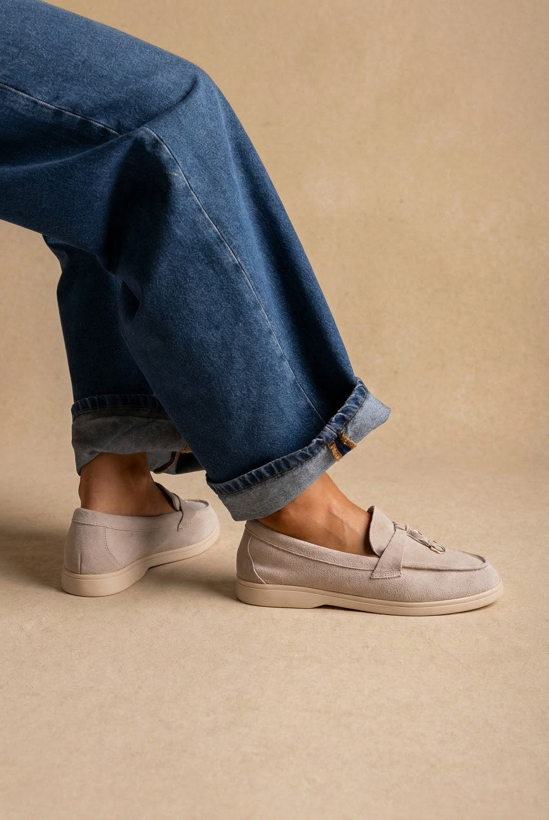 Light taupe grey suede loafers with a strap and tassel detail and cream flat sole, worn with cuffed wide-leg jeans