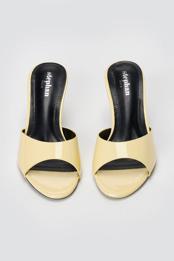 Pair of pale yellow patent leather heeled mules with open toes and black insoles, top-down view