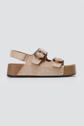 Beige suede platform sandal with two round buckles, slingback strap, gold studs and cork-style sole, side view