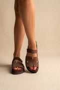 Brown suede chunky platform slides with cut-out straps and a back strap detail, front view worn on a model