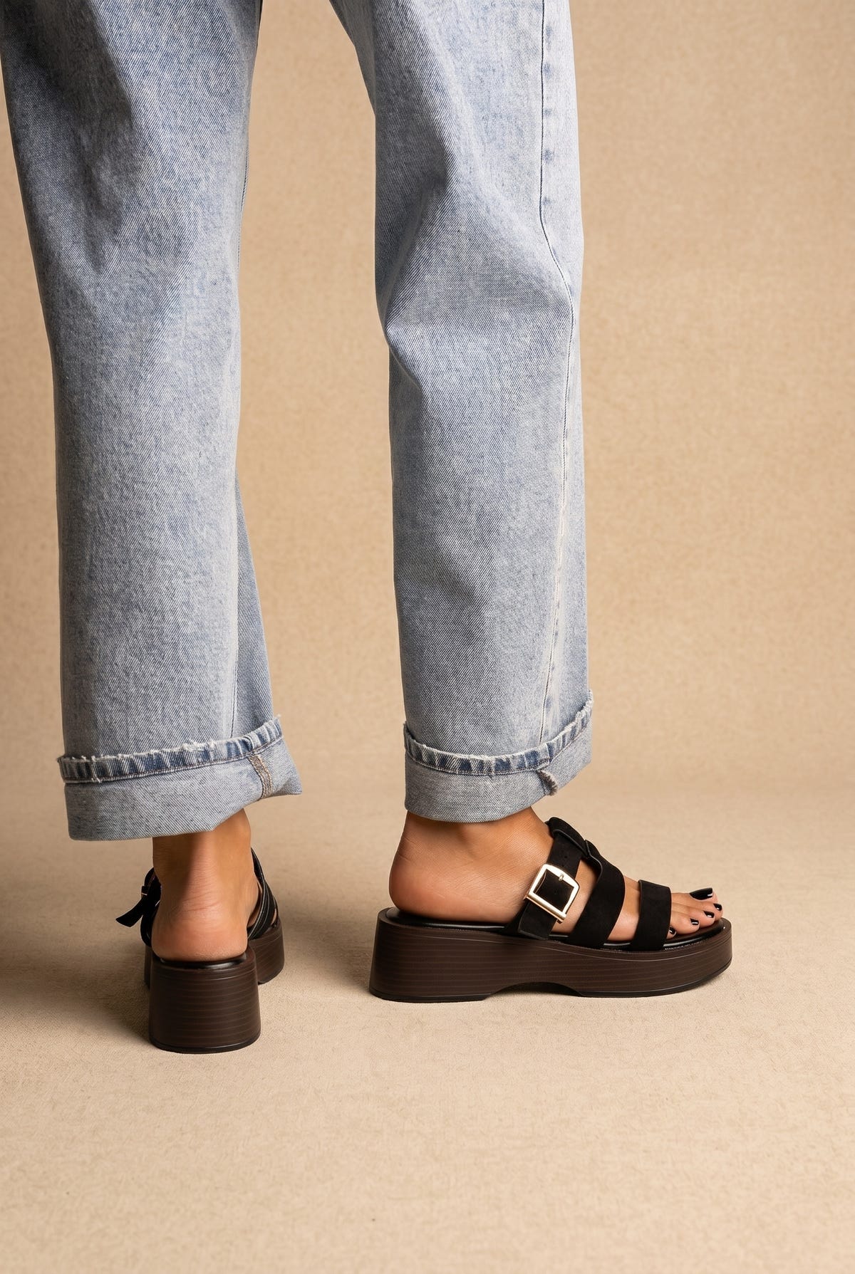 Black platform slide sandals with three straps and silver buckle on a dark brown stacked sole, back view