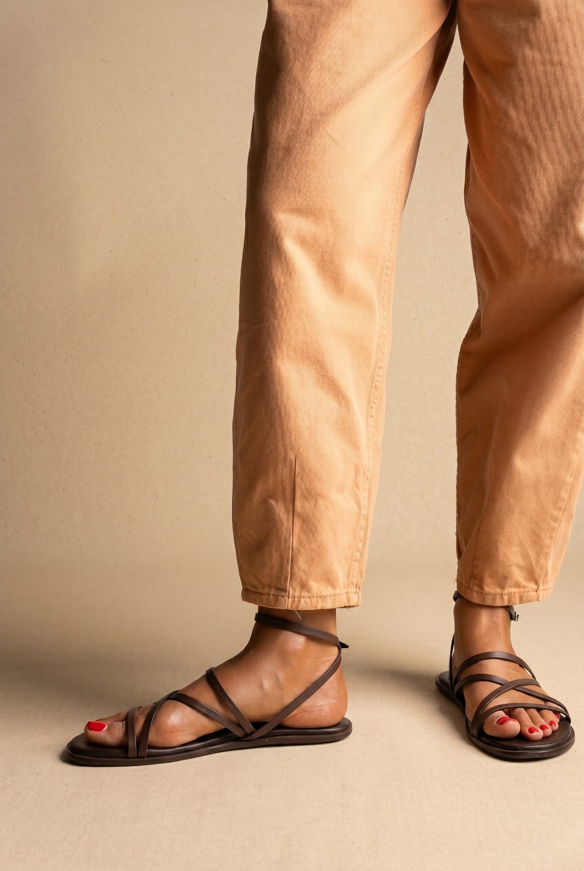 Dark brown leather flat strappy sandals with multiple thin straps and ankle strap, front view on a model