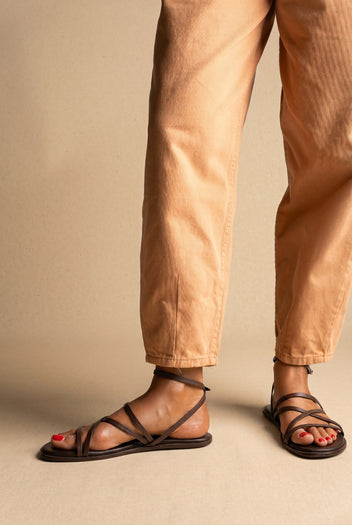 Dark brown leather flat strappy sandals with multiple thin straps and ankle strap, front view on a model