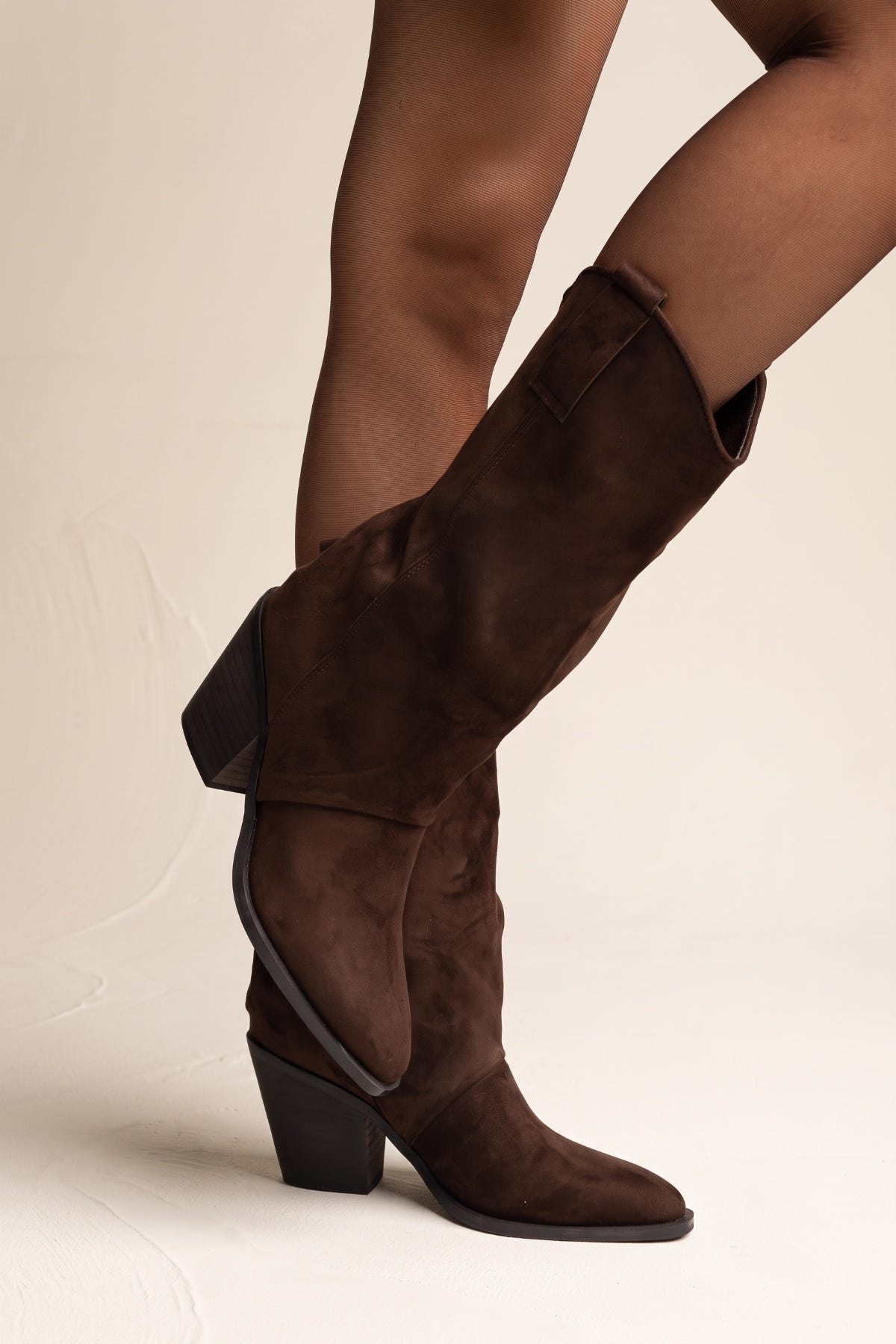 Model wearing brown suede western gaiter boots with the top folded down over sheer tights
