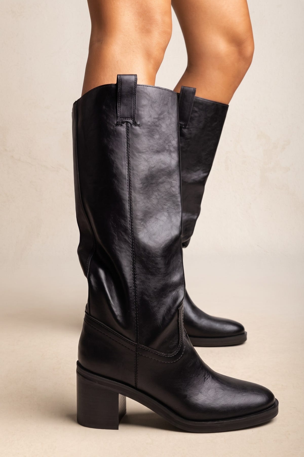 Black leather knee-high boots with pull tabs, stitched details and chunky block heel, side view, worn on model