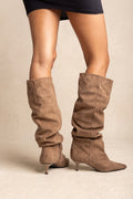 Model wearing slouchy camel suede boots with pointed toes and slim kitten heels in a scrunched fit