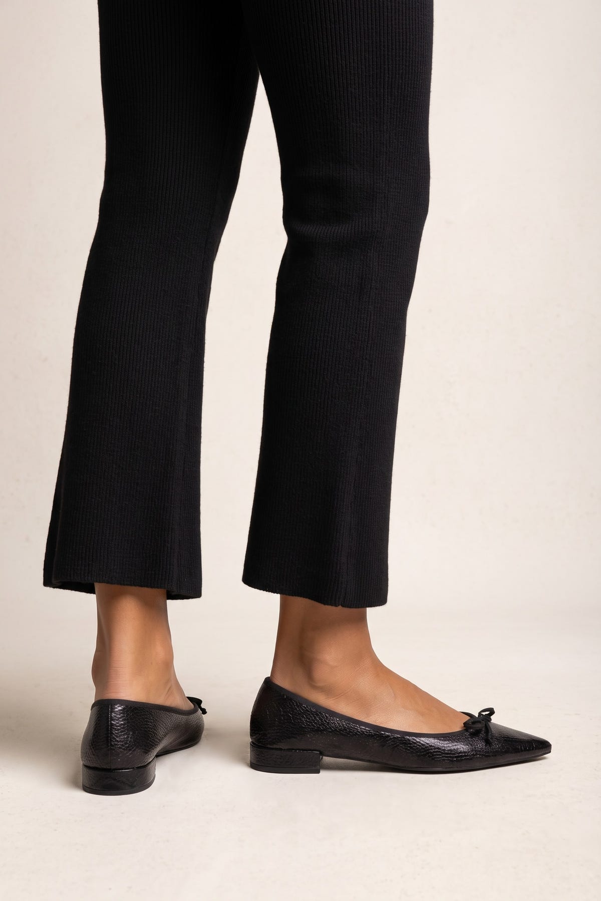 Black snake-embossed leather pointed flats with bow detail and low block heels, back and side view worn on model