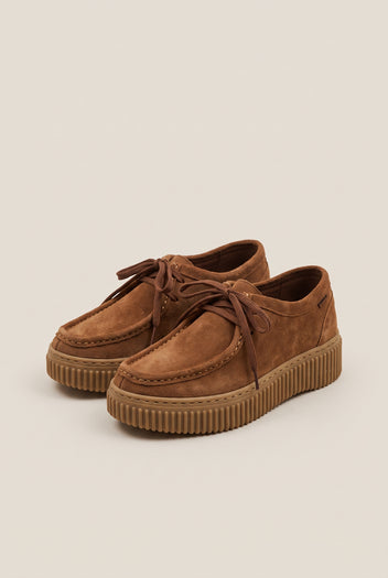 Tan suede lace-up creeper shoes with crepe rubber sole, pair in low-angle view on a light beige background