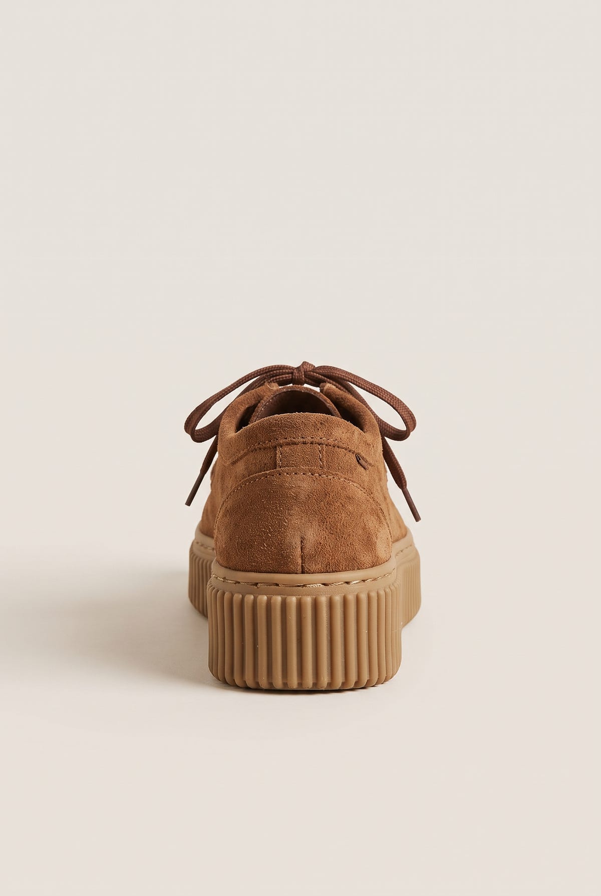 Tan suede lace-up creeper shoe with crepe rubber sole, front view on a light beige background