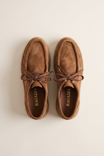 Tan suede lace-up creeper shoes with crepe rubber sole, pair in top-down view on a light beige background