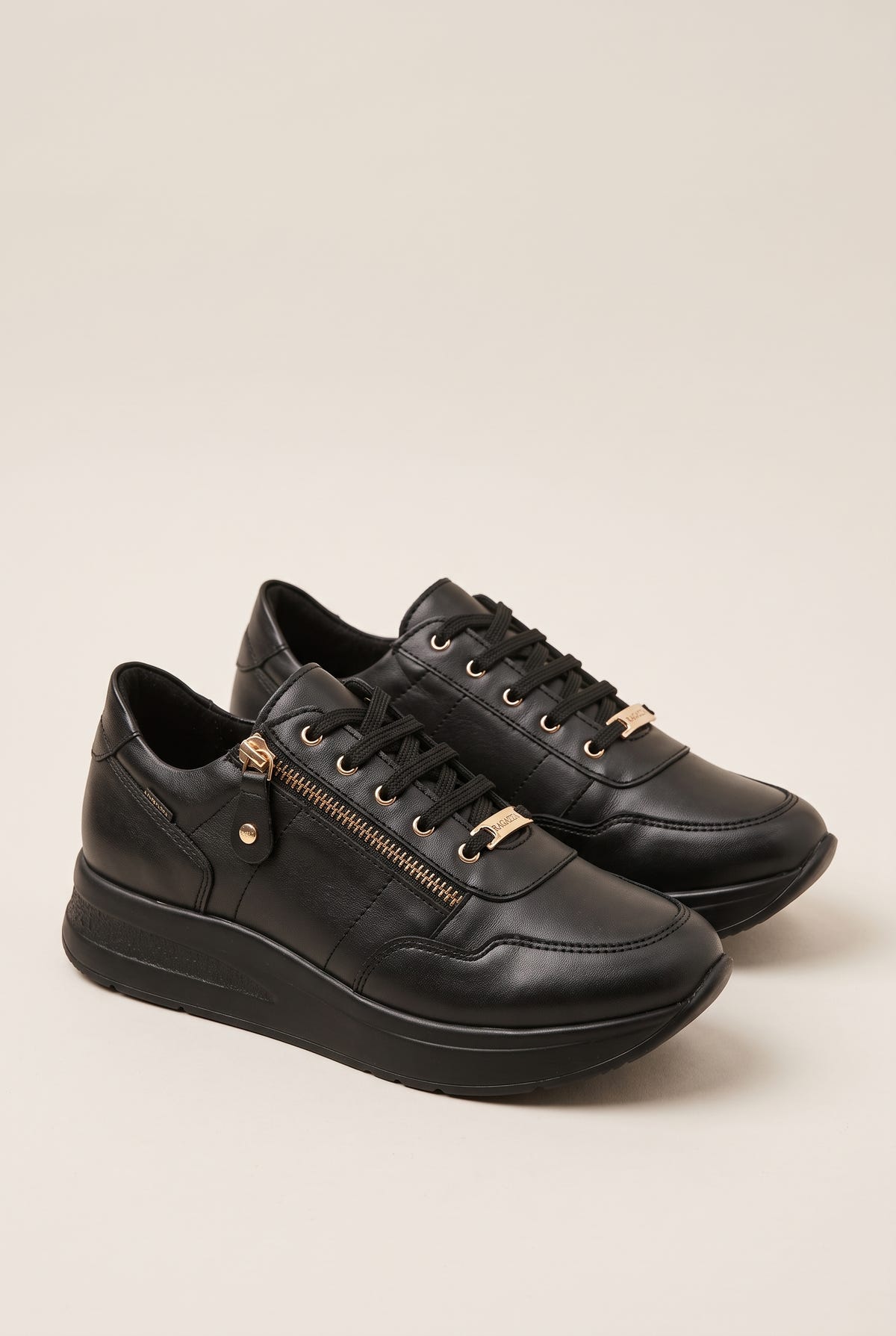 Pair of black leather lace-up wedge sneakers with side zip and gold lace tip detail, three-quarter view