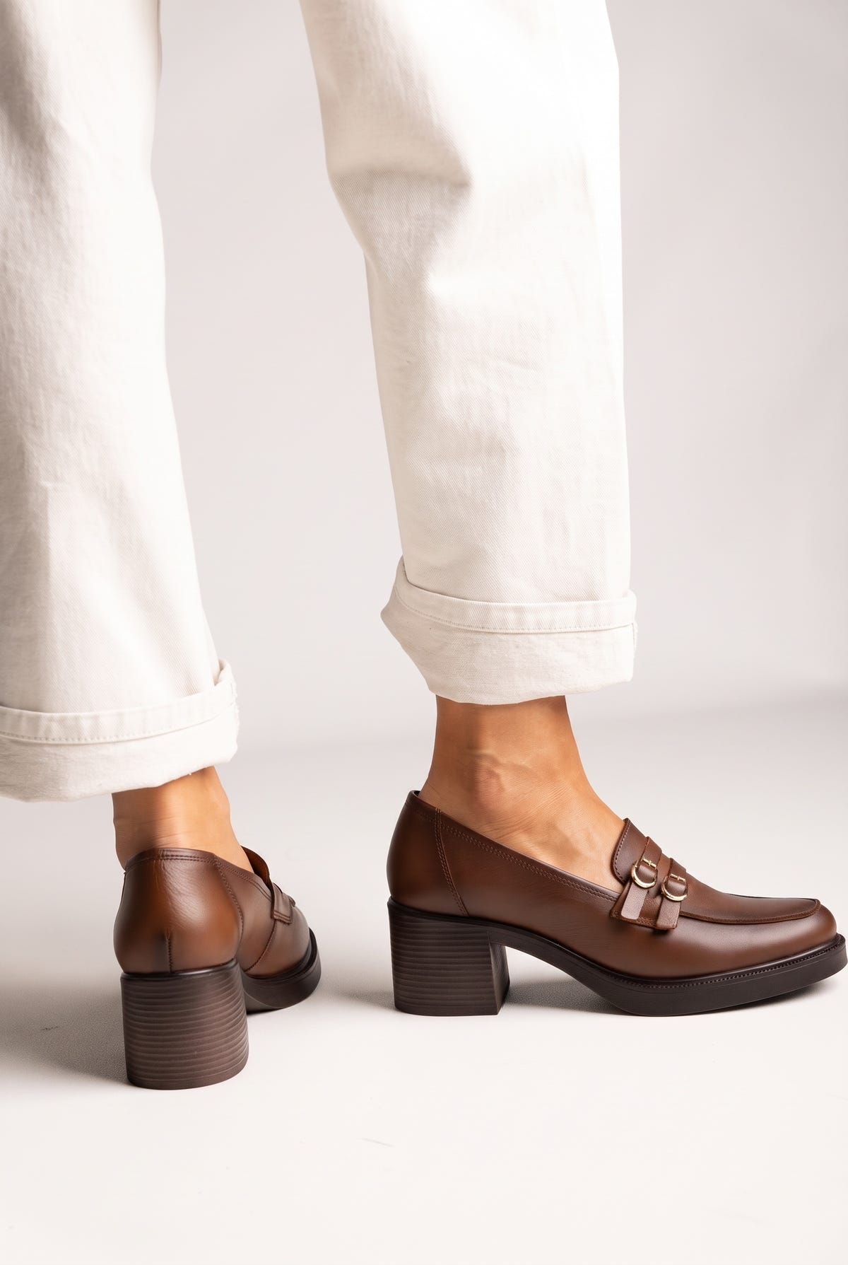 Brown smooth leather block heel loafers with double buckle straps and chunky dark sole, side and back view, worn on model